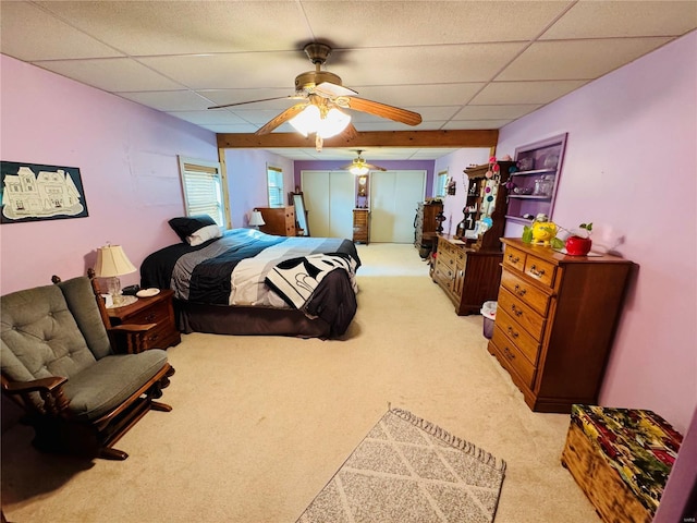 carpeted bedroom with a drop ceiling and ceiling fan