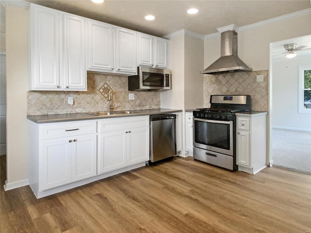 kitchen featuring sink, wall chimney exhaust hood, light hardwood / wood-style flooring, stainless steel appliances, and decorative backsplash