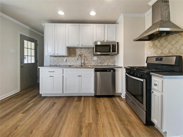 kitchen featuring stainless steel appliances, wall chimney exhaust hood, sink, and white cabinetry