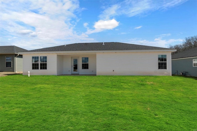 back of property featuring a lawn and roof with shingles