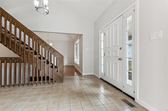 tiled foyer featuring vaulted ceiling, a wealth of natural light, and an inviting chandelier