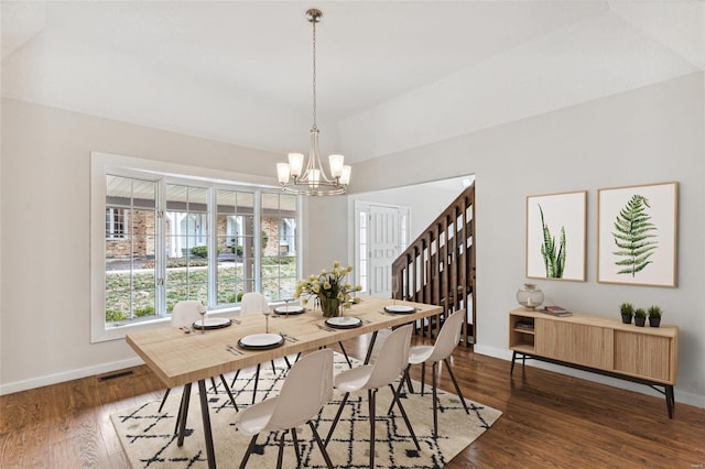 dining room with dark hardwood / wood-style flooring, lofted ceiling, and an inviting chandelier