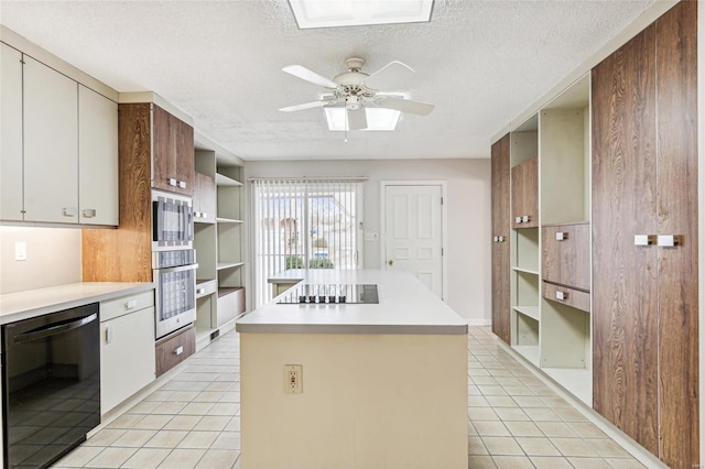 kitchen featuring a textured ceiling, ceiling fan, black appliances, a kitchen island, and light tile patterned flooring