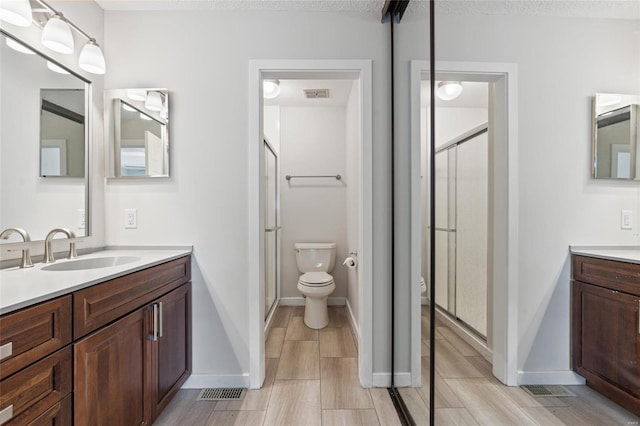 bathroom with hardwood / wood-style floors, vanity, toilet, and a shower with shower door