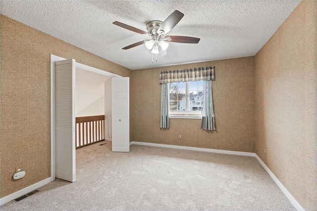 unfurnished bedroom featuring ceiling fan, carpet floors, and a textured ceiling