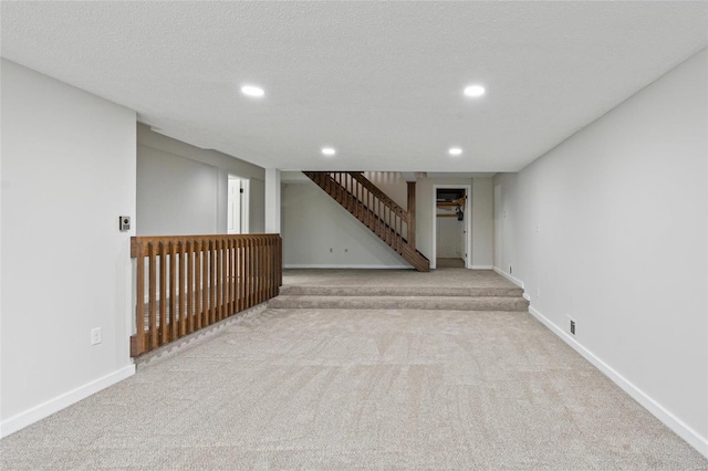 basement featuring light colored carpet and a textured ceiling