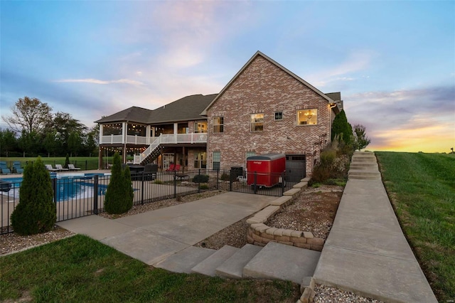 back house at dusk with a pool side deck and a patio area