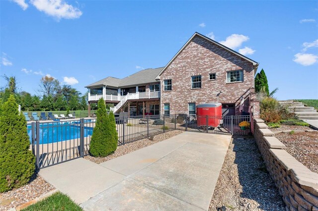 back of house featuring a fenced in pool and a balcony