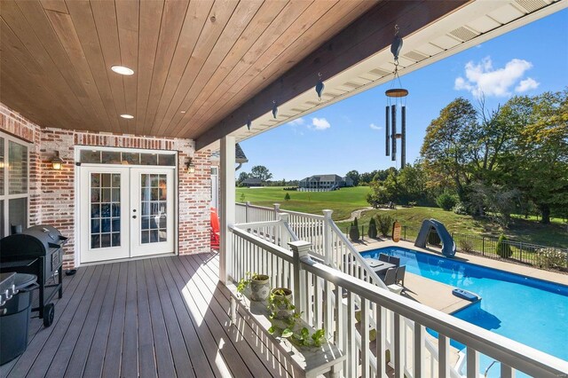 deck with a fenced in pool, french doors, and grilling area