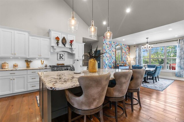 kitchen with high vaulted ceiling, white cabinetry, and wood-type flooring