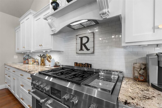 kitchen with light stone counters, dark hardwood / wood-style flooring, white cabinetry, high end stove, and backsplash