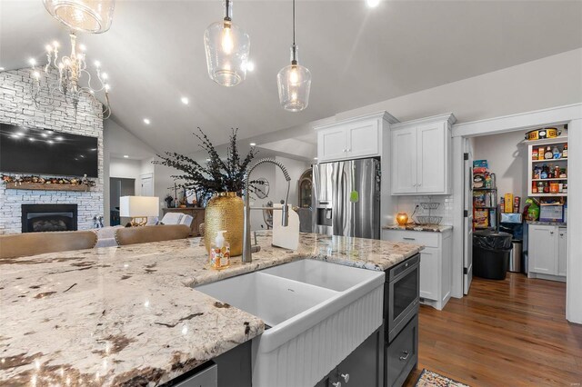 kitchen with decorative light fixtures, lofted ceiling, dark hardwood / wood-style floors, appliances with stainless steel finishes, and white cabinetry