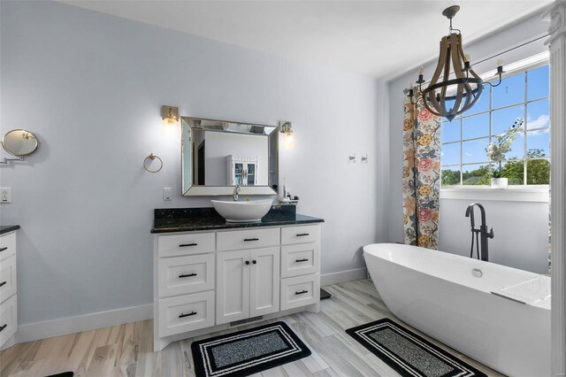 bathroom with a chandelier, hardwood / wood-style floors, a tub, and vanity