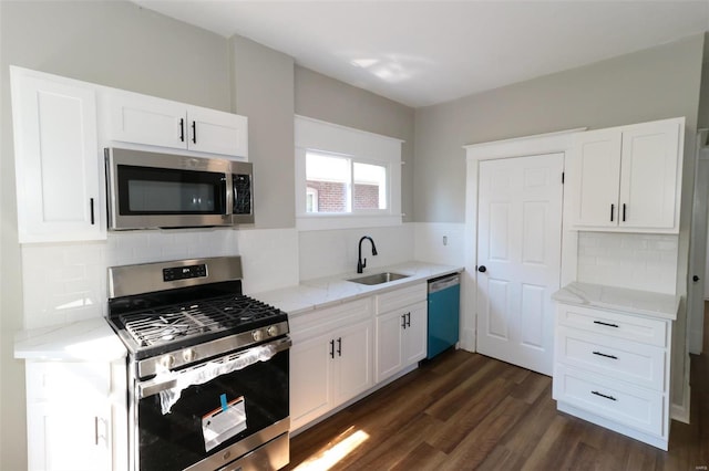 kitchen with dark wood-type flooring, white cabinets, light stone countertops, stainless steel appliances, and sink