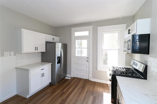 kitchen with appliances with stainless steel finishes, dark hardwood / wood-style floors, white cabinetry, and decorative backsplash