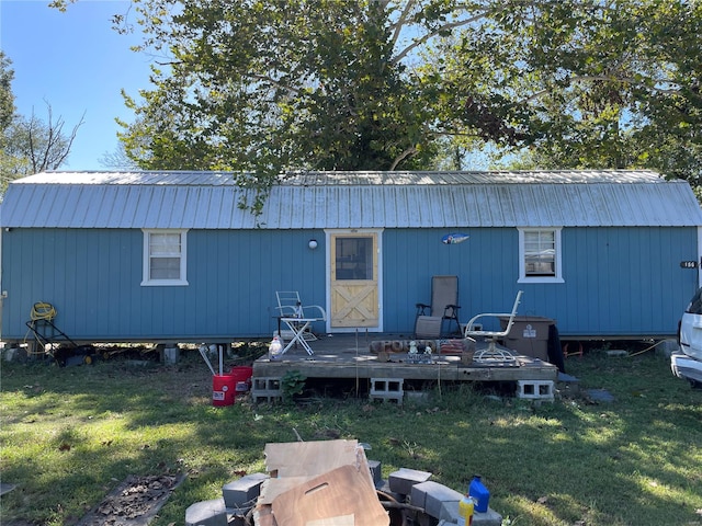 rear view of property featuring a wooden deck, a lawn, and a shed