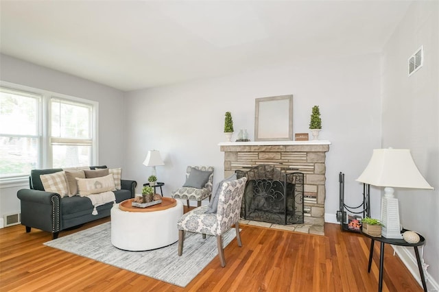 living room featuring a stone fireplace and hardwood / wood-style floors