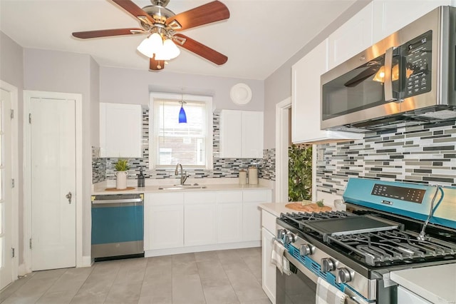 kitchen with decorative backsplash, sink, stainless steel appliances, light tile patterned floors, and white cabinetry