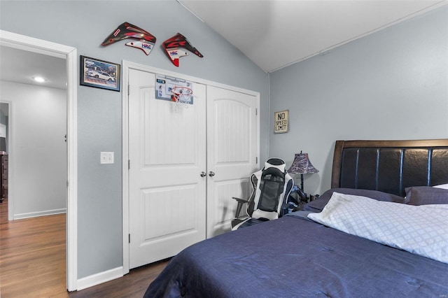 bedroom with a closet, dark hardwood / wood-style floors, and vaulted ceiling