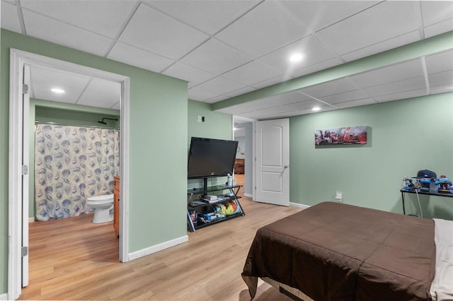 bedroom with light hardwood / wood-style floors, ensuite bathroom, and a paneled ceiling