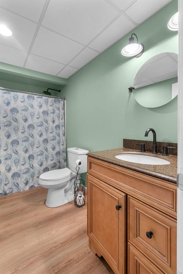 bathroom featuring toilet, a shower with curtain, hardwood / wood-style floors, vanity, and a paneled ceiling