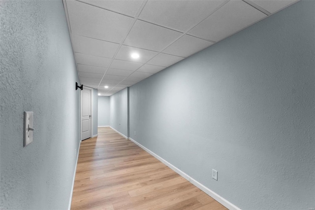 hall with light hardwood / wood-style floors and a drop ceiling