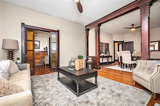 living room featuring ceiling fan, hardwood / wood-style floors, and ornate columns