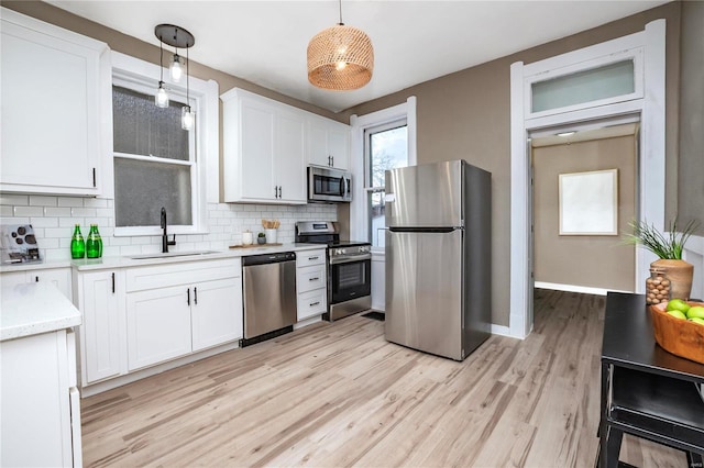 kitchen with sink, white cabinetry, decorative light fixtures, appliances with stainless steel finishes, and backsplash