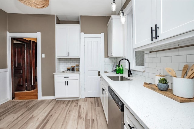 kitchen featuring white cabinetry, sink, stainless steel dishwasher, and hanging light fixtures