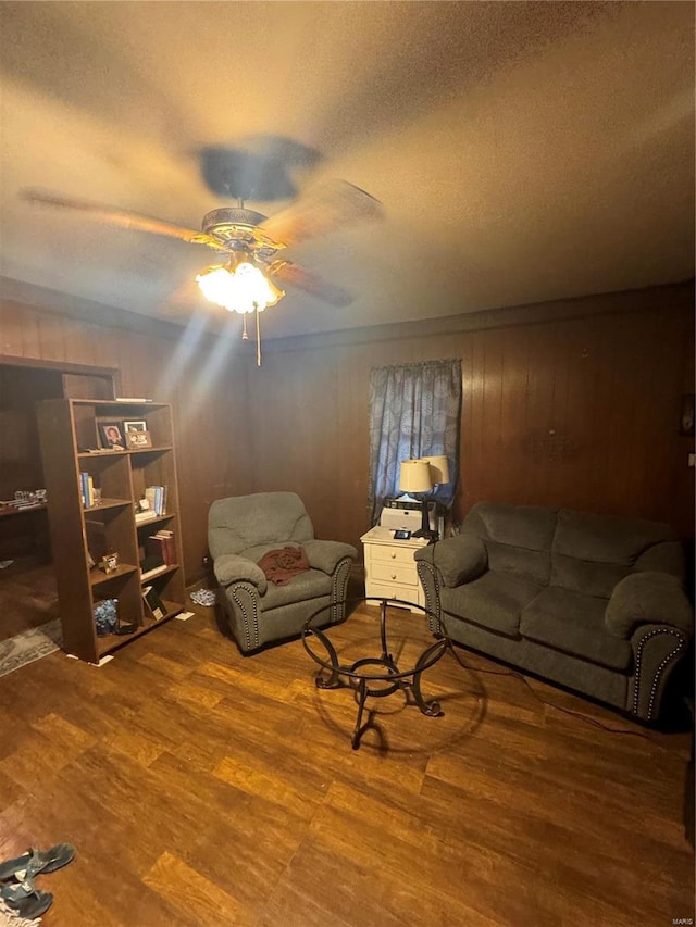 unfurnished living room featuring ceiling fan, a textured ceiling, wood walls, and hardwood / wood-style floors