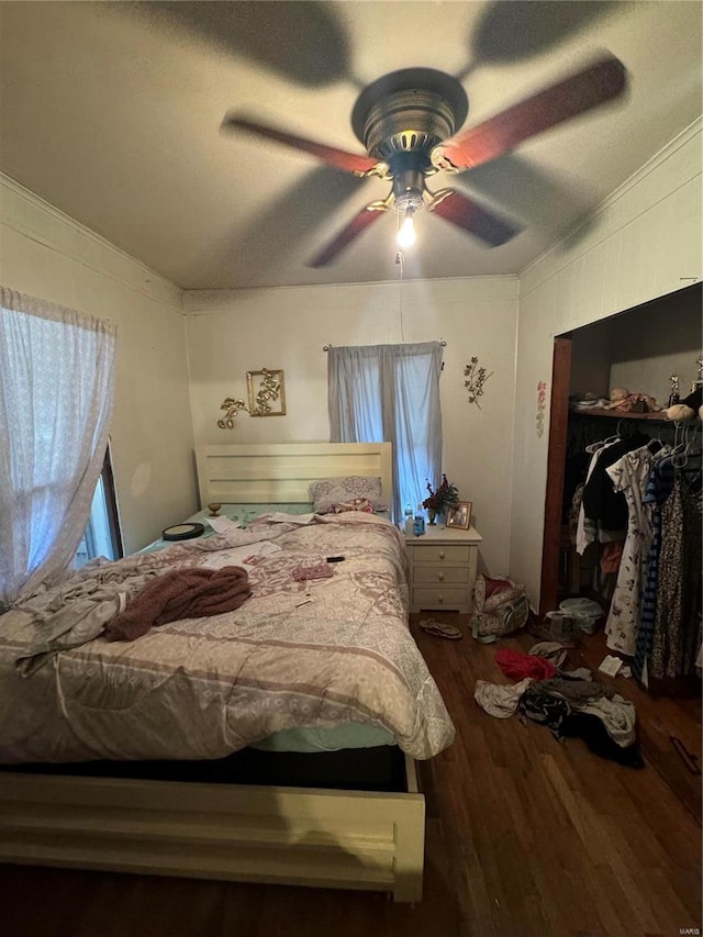 bedroom with ornamental molding, dark hardwood / wood-style flooring, ceiling fan, and a closet