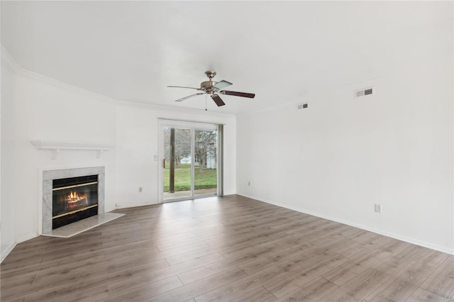 unfurnished living room with ceiling fan, wood-type flooring, a fireplace, and ornamental molding