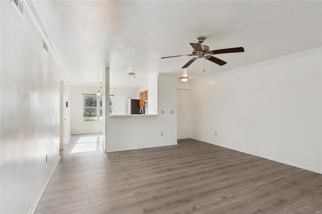 unfurnished living room with ceiling fan, light wood-type flooring, and ornamental molding