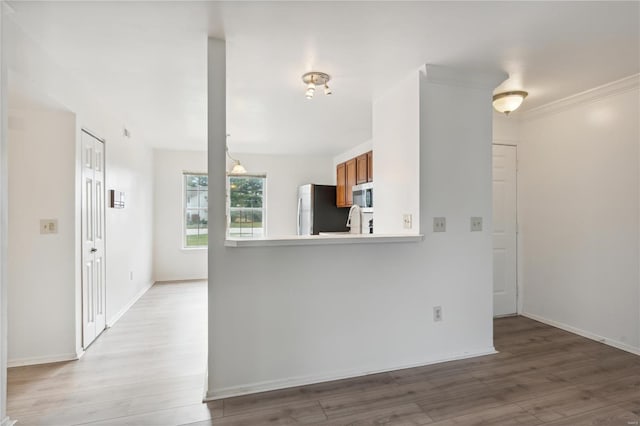 kitchen featuring appliances with stainless steel finishes, light wood-type flooring, and ornamental molding