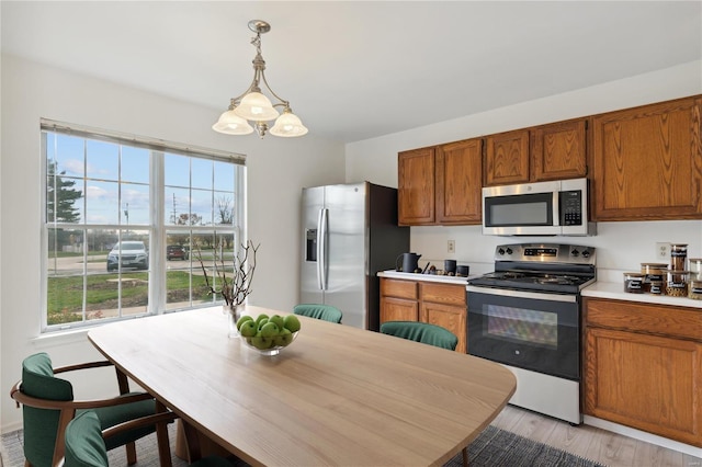 kitchen with decorative light fixtures, light wood-type flooring, and appliances with stainless steel finishes