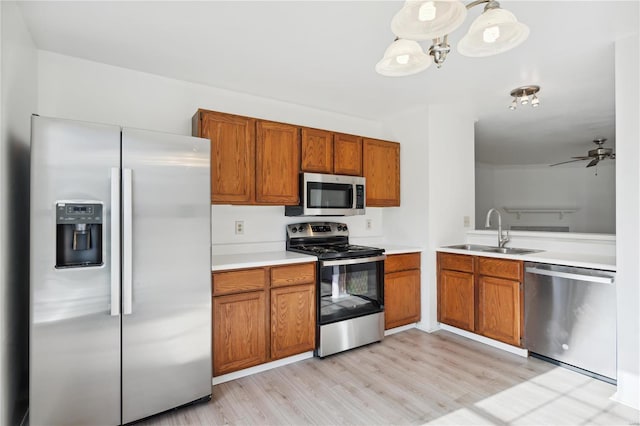 kitchen with hanging light fixtures, sink, ceiling fan, light wood-type flooring, and appliances with stainless steel finishes