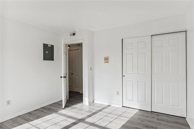 unfurnished bedroom with light hardwood / wood-style floors, electric panel, and a closet