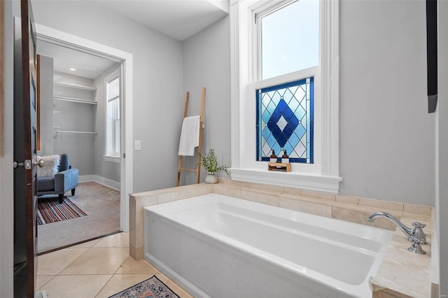 bathroom featuring a washtub, tile patterned floors, and a healthy amount of sunlight