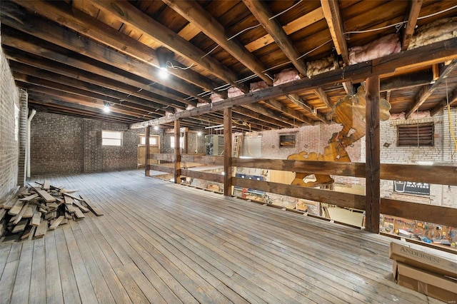 basement featuring brick wall and hardwood / wood-style flooring