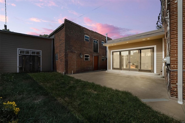 back house at dusk with a yard and a patio area