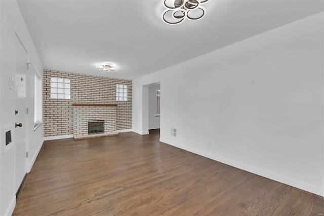 unfurnished living room featuring dark hardwood / wood-style flooring and brick wall