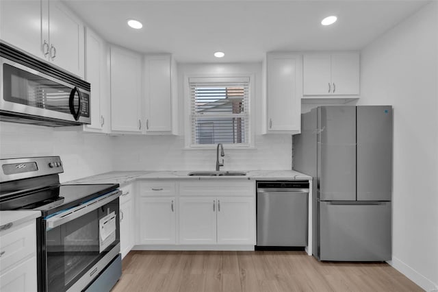 kitchen with light wood-type flooring, white cabinetry, sink, and appliances with stainless steel finishes