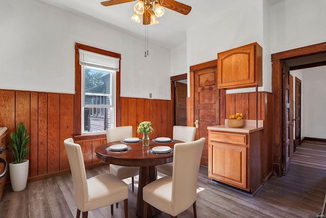 dining room featuring wood walls, hardwood / wood-style floors, and ceiling fan