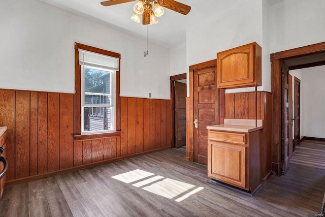 kitchen featuring wood walls, ceiling fan, and dark hardwood / wood-style floors