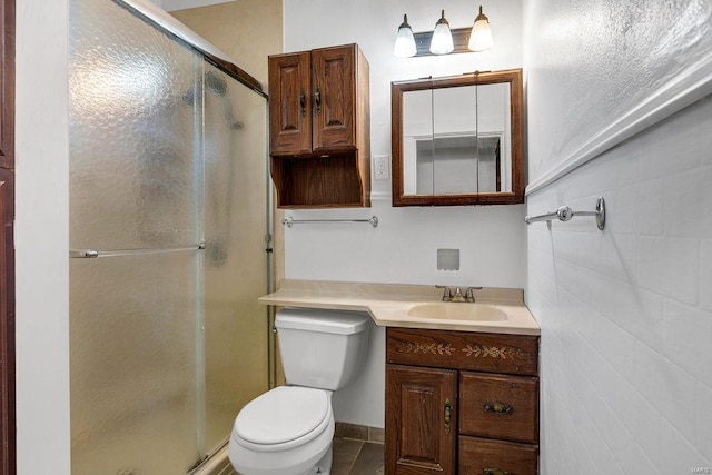 bathroom featuring tile patterned flooring, a shower with door, toilet, and vanity