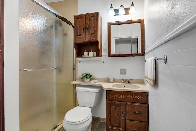 bathroom featuring tile patterned flooring, a shower with door, vanity, and toilet