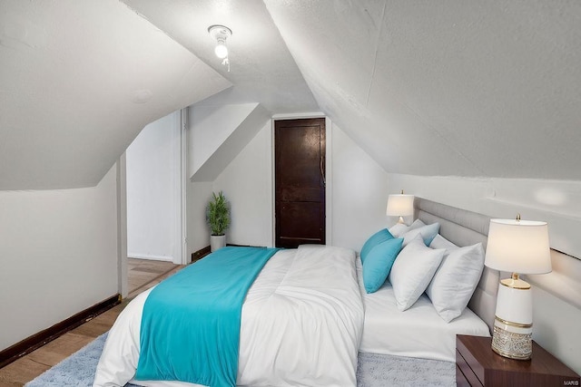 bedroom with light wood-type flooring and lofted ceiling