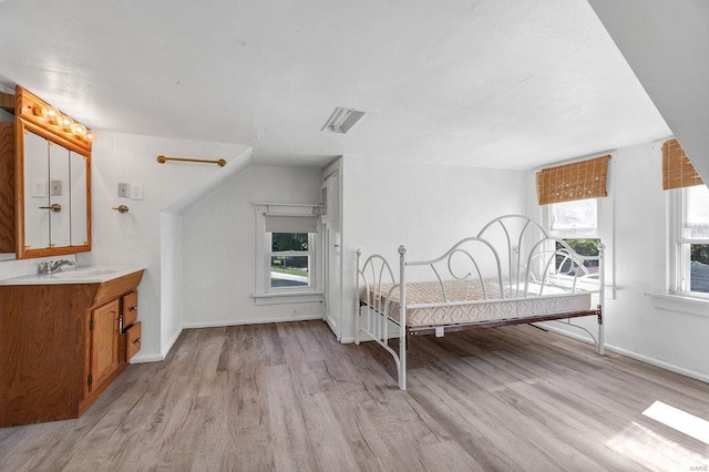 unfurnished bedroom featuring light wood-type flooring, multiple windows, and sink