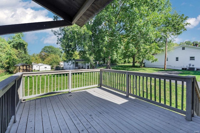 wooden deck featuring a lawn and a storage shed