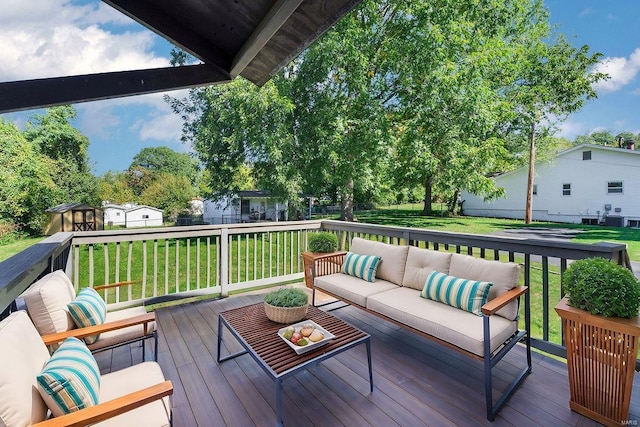 wooden terrace featuring an outdoor living space, a storage shed, and a yard